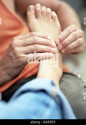 Giovane uomo massaggiare una donna di piedi Foto Stock