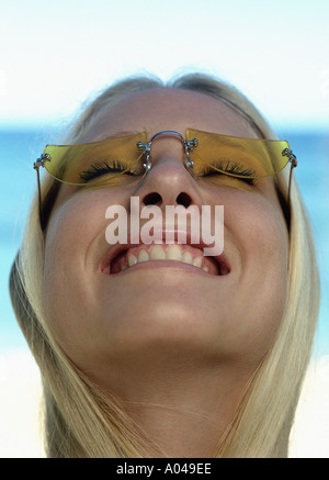 Ritratto di una giovane donna con capelli biondi indossando occhiali da sole e sorridente Foto Stock