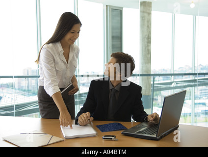 Imprenditore lavora con il computer portatile, parlando al collega di sesso femminile Foto Stock