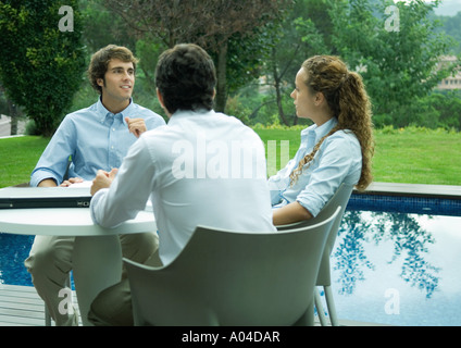 Casualmente vestito giovani dirigenti lavorando vicino al bordo della piscina Foto Stock