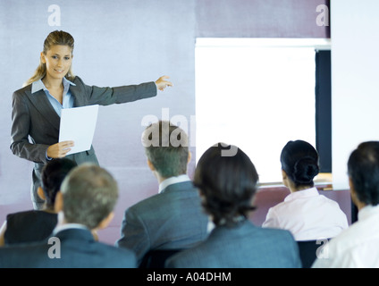 I dirigenti seduti in seminario, donna in piedi rivolta verso il gruppo, gesticolando in schermata Foto Stock