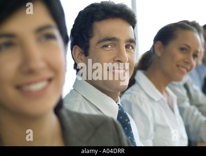 Soci di affari in fila uno uomo sorridente in telecamera Foto Stock