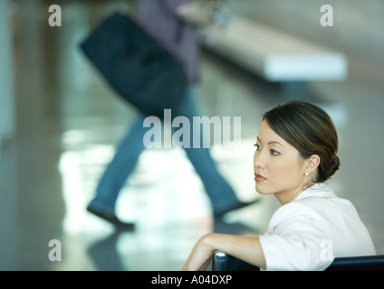 Donna seduta nella sala di attesa di un aeroporto Foto Stock