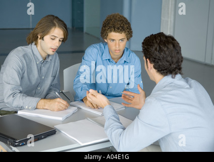 Tre giovani uomini a lavorare a tavola Foto Stock