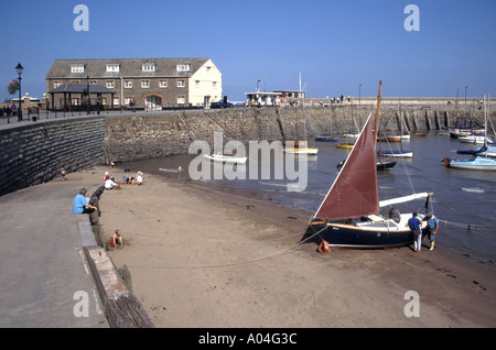 Minehead lungomare in pietra porto parete mare & passeggiata estate cielo blu giorno persone in spiaggia vacanza in famiglia sabbia barca a vela & equipaggio Somerset Inghilterra UK Foto Stock