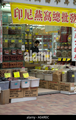 Dh Bonham Strand West Sheung Wan HONG KONG la medicina di erbe shop essiccato health foods negoziante utilizzando la calcolatrice cinese Foto Stock