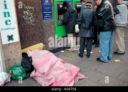 La persona senza dimora addormentato accanto al cash dispenser a Oxford Street Londra Centrale. Foto Stock