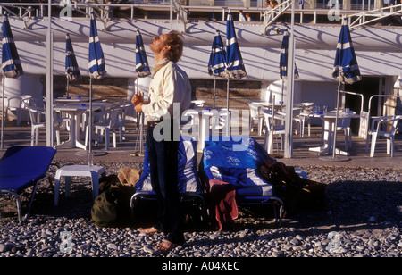 Un uomo sulla spiaggia di Nizza Francia godendo gli ultimi raggi di sole prima di prendere un volo alla fine di una vacanza Foto Stock