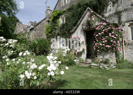 Le rose intorno alla porta di una vecchia fattoria in cotswold frazione di Callmsden su un inizio giornata d'estate Foto Stock