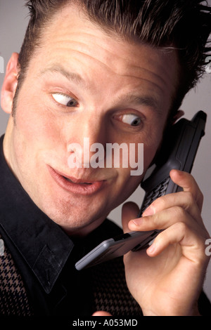Imprenditore parlando al telefono parlando di divertimento notizie entusiasmanti facendo una faccia buffa espressione con un fattore wow Foto Stock