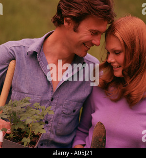 Close up di un auburn capelli uomo e donna sorridente ad ogni altro con attrezzi da giardino in mano Foto Stock