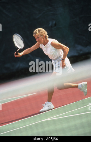 Un pensionato anziano donna giocando a tennis all'aperto Foto Stock