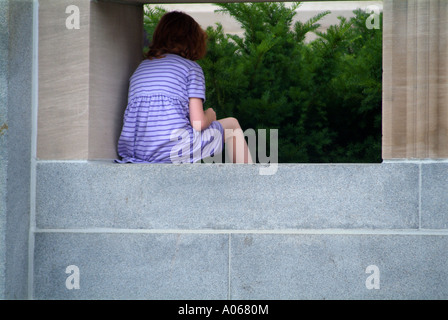 Snella ragazza in viola abito a strisce si siede sul muretto, ascoltando il portello di concerto, Ann Arbor, MI Foto Stock