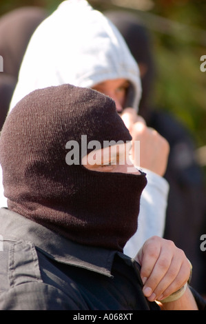 Vista del profilo di rapinatori mascherati in balaclava con abbigliamento tattico nero e calotte, concentrandosi sullo sguardo intenso di un individuo. Foto Stock