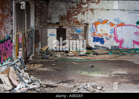 Graffiti verniciato a spruzzo sulle pareti all'interno di un vecchio deserta magazzino industriale a Dundee, Regno Unito Foto Stock