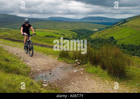 Femmina mountain biker su un cingolo sopra Wandale nel Howgill Fells in Cumbria Foto Stock