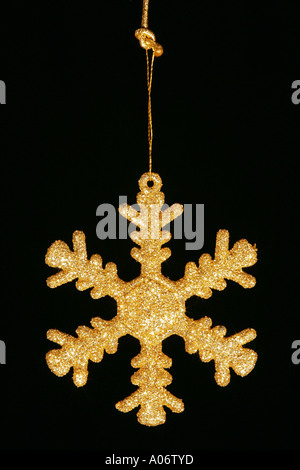 Primo piano della golden scintillante Xmas stella di Natale decorazione a fiocco di neve contro uno sfondo nero Foto Stock