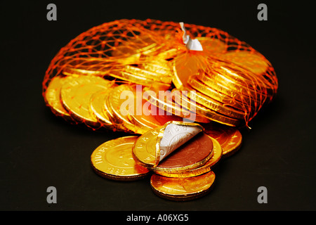 Il cioccolato al latte novità monete con brillante lucido lamina dorata involucri in una borsa a rete su sfondo nero, regalo di Natale per i bambini REGNO UNITO Foto Stock