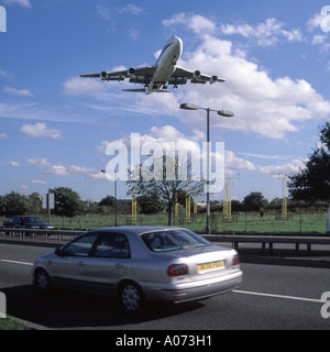 Dall'aeroporto Heathrow di Londra a bassa Battenti aereo jet su approccio di atterraggio passa sopra il traffico in movimento lungo una strada a doppia carreggiata Foto Stock