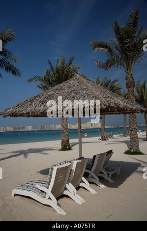 Jumeirah Palm in costruzione a Dubai visto attraverso il servizio spiaggia con ombrelloni e sedie a sdraio emirati arabi uniti medio oriente emirati arabi uniti Foto Stock