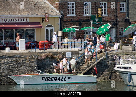 Padstow harbour promenade di piccole imbarcazioni a posti barca in una calda giornata estiva con persone che arrivano in banchina da viaggio in motoscafo Foto Stock