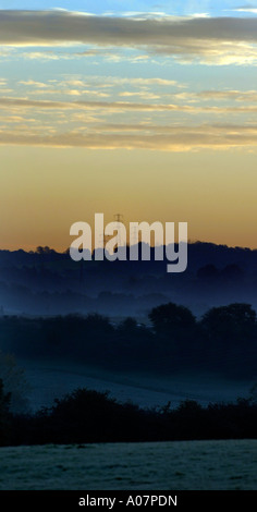 Sunrise su tralicci di energia elettrica in una nebbia e coperto di brina Teme Valley Worcestershire Foto Stock