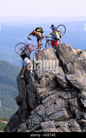 Tre uomini scalare una montagna con le loro mountain bike nel Monte Carleton Parco Provinciale New Brunswick Canada Foto Stock