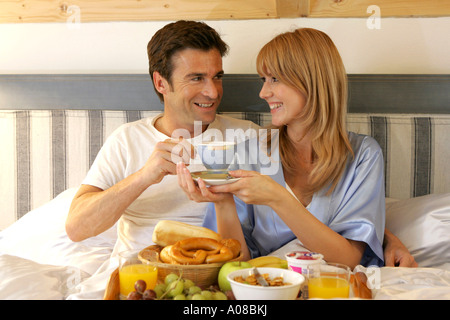 Paar beim gemeinsamen Fruehstueck im Bett, giovane avente insieme per la prima colazione a letto Foto Stock