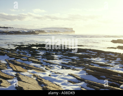 Dh Birsay Bay BIRSAY ORKNEY neve sulla spiaggia e Marwick testa costa della Scozia tramonto in inverno rock Foto Stock