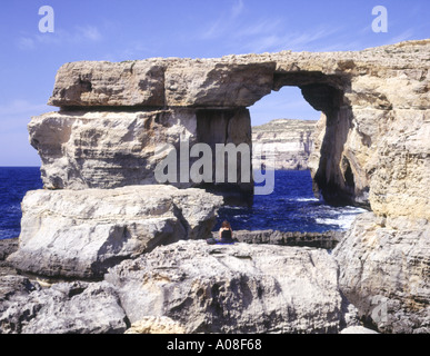 Dh Azure Window Dwejra Point GOZO ragazza seduta sulla roccia a guardare di roccia naturale sul mare di arco Foto Stock