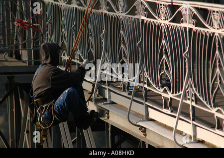 Femmina scalatore industriale pulizia lontano la vecchia vernice con un powertool Foto Stock