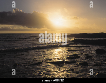 Dh baia di Skaill SANDWICK ORKNEY Sun dietro le nuvole tramonto sul mare e la spiaggia rocciosa e rocce