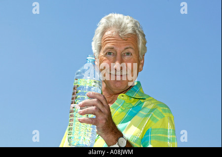 Weisshaariger Mann am Strand trinkt Mineralwasser, uomo Senior presso la spiaggia di bere acqua minerale Foto Stock