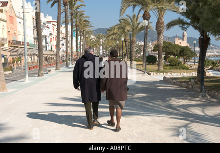 Coppia di mezza età facendo una passeggiata sul lungomare di Sitges, Spagna in inverno Foto Stock