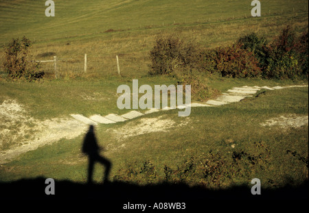 Ombra di un camminatore sui bastioni superiori del Forte di Cissbury dell'Età del ferro, vicino a Findon West Sussex, Inghilterra meridionale, Regno Unito. Foto Stock