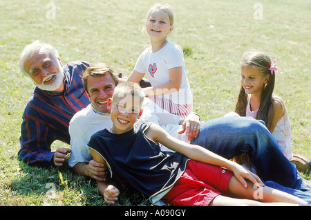 Nonno e padre con bambini sdraiati su un prato Foto Stock