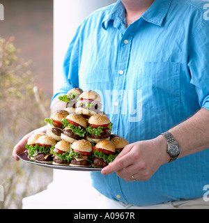 L'uomo portante la lastra di hamburger di piccole dimensioni Foto Stock