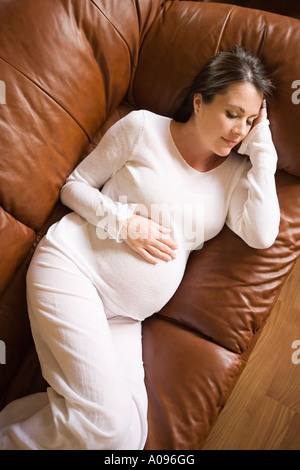 Donna incinta che dorme sul divano Foto Stock