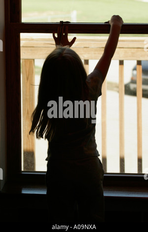 Ragazza giovane sbloccando la blocca in uscita un incendio casa sicura attraverso una seconda storia finestra su un deck Foto Stock