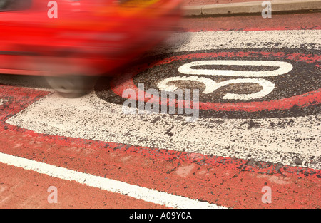 Una macchina passa sopra un usurato trenta miglia per ora gli avvisi di velocità dipinta sul manto stradale Regno Unito Foto Stock