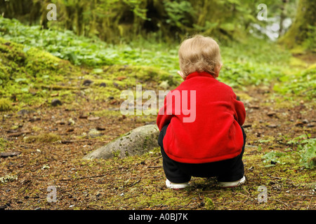 Ragazza giovane accovacciata sul suolo della foresta Verlot Campeggio Mt Baker Snoqualmie Foresta Nazionale di Washington (USA) Foto Stock