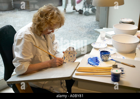 Donna pittura una piastra a 'Royal Copenaghen" di porcellana del negozio della fabbrica, Copenhagen, Danimarca Foto Stock