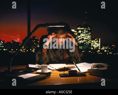 Woman Executive lavora fino a tardi nel suo ufficio, con forse lo stress, mal di testa e affaticamento. Foto Stock