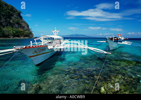 Outrigger barche o banca ormeggiate nei bassifondi vicino ad una spiaggia grande La Laguna Beach Puerto Galera Mindoro Filippine Foto Stock