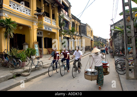 Il Vietnam Hoi An Old Town Pho Nguyen Thai Hoc Street ciclisti e snack street venditore che trasportano derrate alimentari in pole Foto Stock