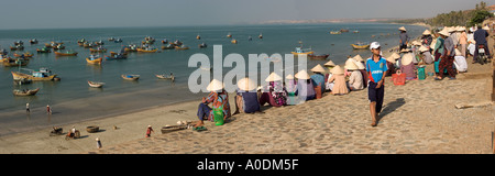 Il Vietnam Mui Ne barche da pesca ormeggiate in Mui Ne Bay come donne attendere per catture da sbarcare panoramic Foto Stock