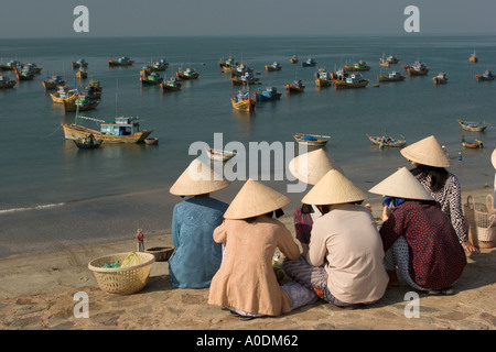 Il Vietnam Mui Ne barche da pesca ormeggiate in Mui Ne Bay come donne attendere per catture da sbarcare Foto Stock