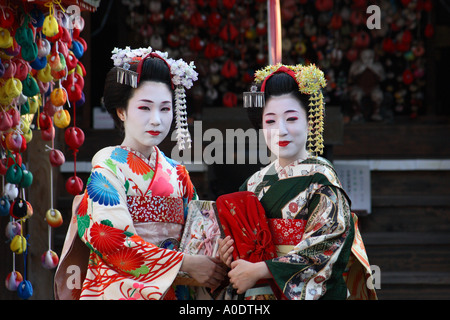 Due maiko - apprendista geisha - visita il sito di un santuario nello storico quartiere di Gion della città di Kyoto, Giappone Foto Stock