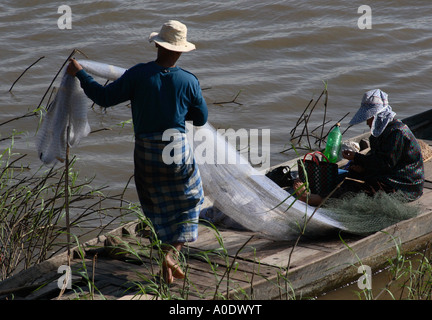 Un pescatore di raddrizzatura le sue reti sulla sua barca ormeggiata sul fiume Tonle Sap nella capitale cambogiana Phnom Penh Foto Stock