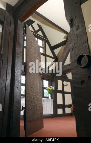 UK property, casa interno, vista attraverso le antiche chiodati in legno scuro porta a soffitto alto con travi di legno scuro camera. Foto Stock
